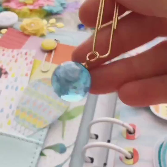 Video of resin sphere with clouds inside, attached to a paper clip